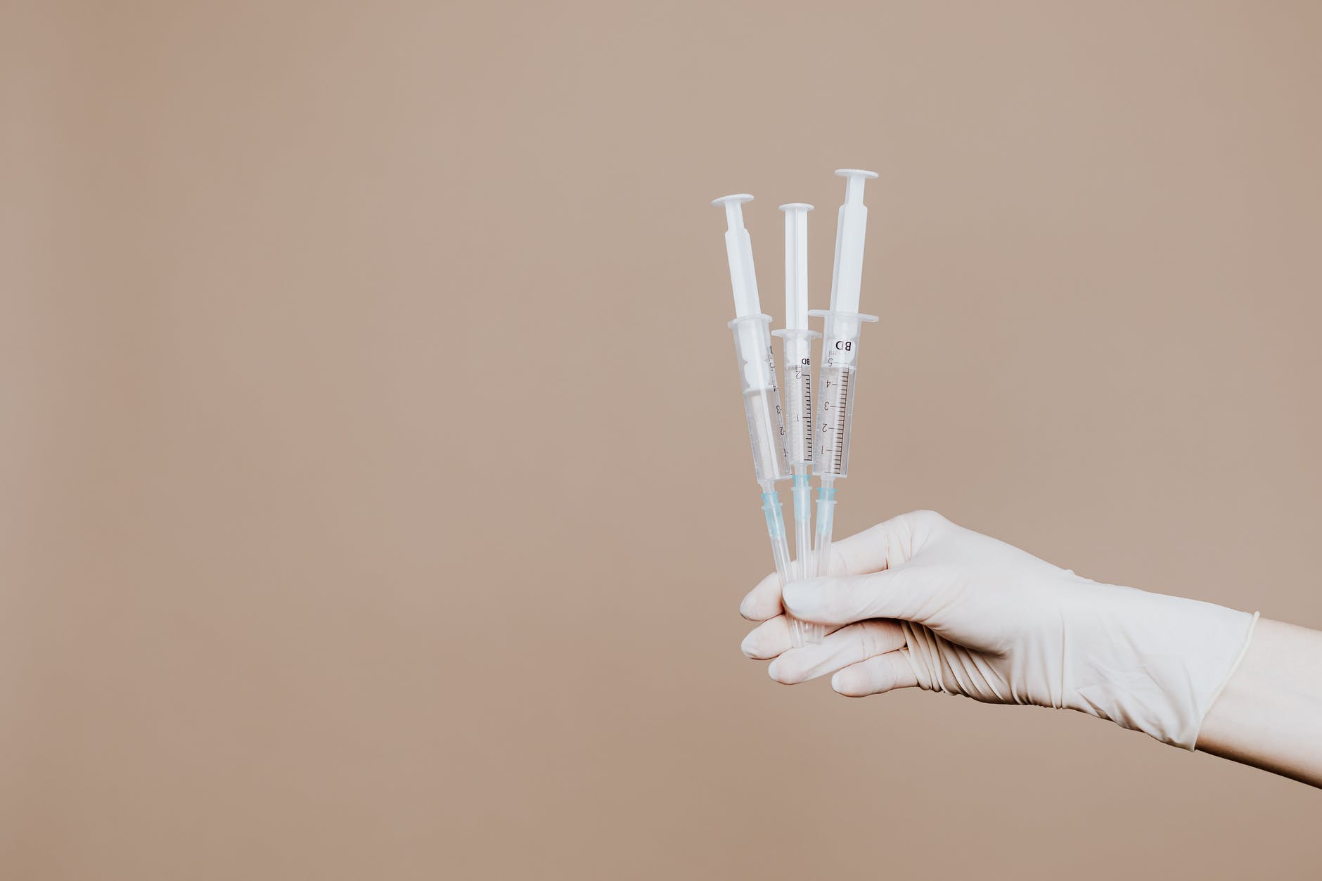 person holding three syringes with medicine