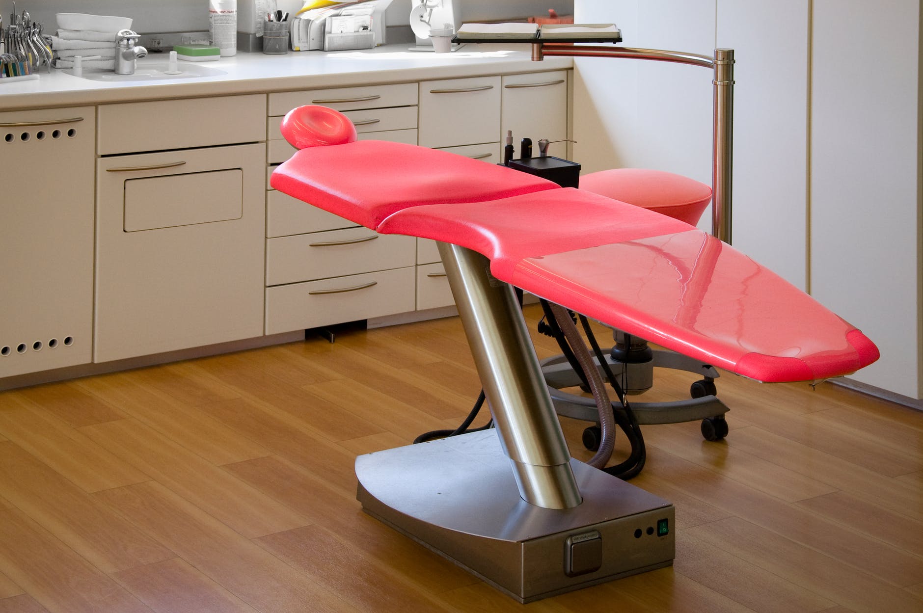 gray metal framed red dental treatment chair